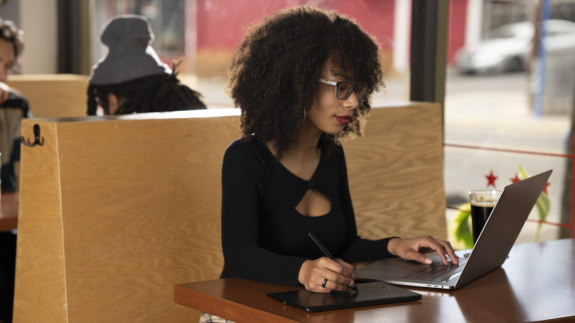 black woman using wacom intuos pro in coffee shop